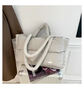 Detailed view of a stylish grey padded puffer tote bag with glossy finish on a suitcase