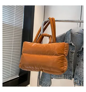 Burnt orange quilted puffer tote bag hanging on a chrome clothing rack detail view