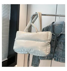 Detailed view of cream glossy puffer tote bag hanging on a metal clothes rack