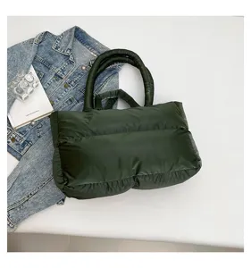 Top view of dark green puffer handbag on minimalist white background with denim jacket
