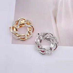 Detailansicht eleganter gold- und silberfarbener runder Broschen mit Strasssteinen.