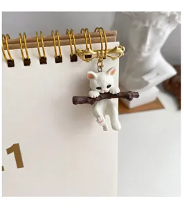 Detail shot of a cute 3D kitten hugging a branch brooch pinned to a white spiral notebook