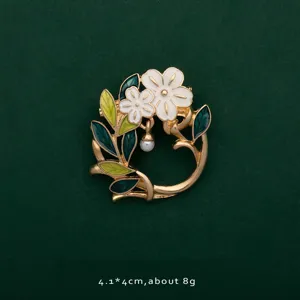 Close-up of an elegant enamel flower wreath brooch featuring white petals and a pearl drop