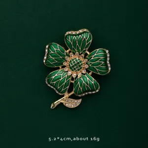 Macro detail of elegant green enamel flower brooch featuring gold trim and sparkling rhinestones
