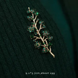Detail view of a vintage green crystal plant branch brooch on dark green knit