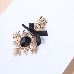 Macro detail of a vintage ornate gold brooch featuring a black gemstone and silk ribbon bow