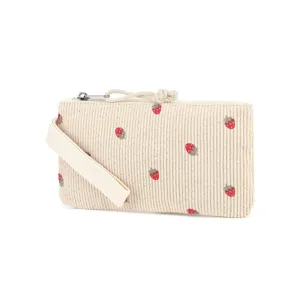 Close-up detail of cream corduroy pencil case featuring embroidered strawberry patterns