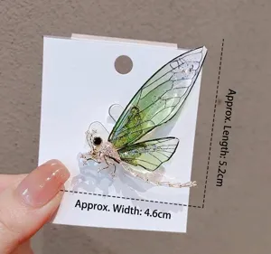 Close-up detail of a green crystal dragonfly brooch with dimensions 5.2cm x 4.6cm.