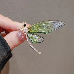 Detailed view of a green dragonfly brooch with crystal accents and glitter wings.