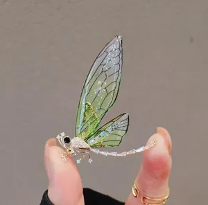 Macro view showing the intricate details of a light luxury green dragonfly brooch with crystals