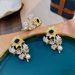 Close-up detail of a dual-tone sunflower brooch with blue gemstone and white pearl