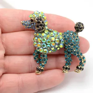 Détail d'une broche en forme de caniche sertie de strass colorés tenue à la main
