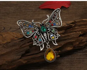 Close-up of vintage hollow butterfly brooch with colorful rhinestones and teardrop pendant