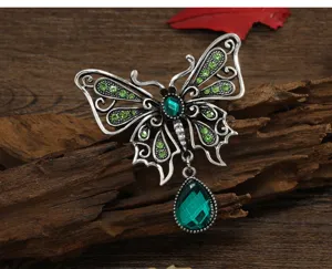 Detailed macro view of a vintage silver butterfly brooch with green teardrop crystal