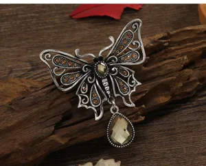 Detailed view of vintage butterfly brooch with amber crystals and teardrop pendant.