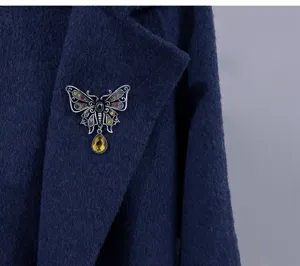 Elegant vintage hollow-out butterfly brooch featuring multi-colored stones on a blue coat