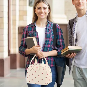 Young woman holding a stylish corduroy lunch bag with cute strawberry patterns in a campus setting