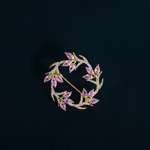 Detailed close-up of a gold-tone floral wreath brooch with pink and white stones