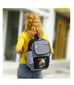 Detailed view of a gingham backpack with floral print on a female model outdoors.