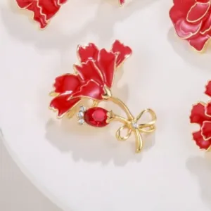 Detail of red enamel flower brooch with golden bow and sparkling rhinestones accent