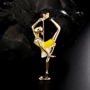 Close-up of elegant gold-toned enamel ballet dancer brooch with yellow and white dress