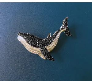 Detail view of a sparkling whale brooch encrusted with black and yellow rhinestones.