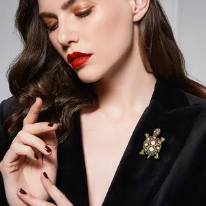 Detailed shot of a vintage gold turtle brooch with colorful stones on a black blazer
