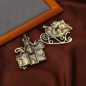 Broches de Noël vintage en forme de château et de traîneau sur tissu marron