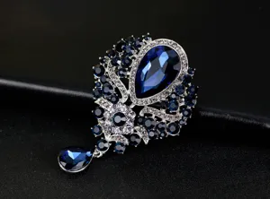 Detailed macro view of a luxury vintage brooch with deep blue teardrop crystal pendant