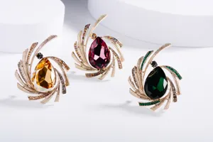 Three elegant crystal brooches with teardrop rhinestones on a white background