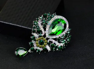 Detailed macro view of the luxury green crystal brooch featuring a dangling teardrop pendant