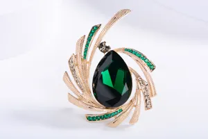 Detail view of elegant starburst brooch with a large emerald green teardrop crystal.
