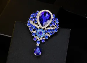 Detailed view of an elegant blue crystal teardrop brooch set on a black textured box