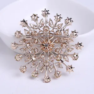 Vue arrière détaillée d'une broche fleur dorée avec fermoir de sécurité et cristaux.