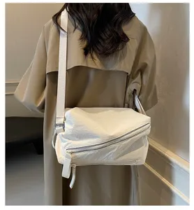 Vista dettagliata di una elegante borsa a tracolla bianca con zip e tracolla regolabile.