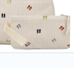 Nahaufnahme eines beige Cord-Mäppchens mit bunt bestickten Flip-Flop-Mustern.