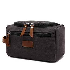 Close-up of a durable charcoal canvas toiletry bag with premium brown leather zipper pulls.