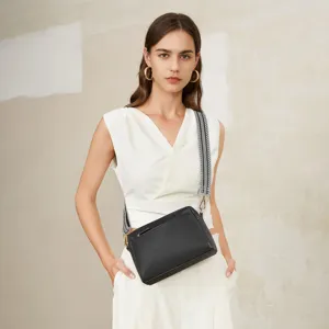 Bolso bandolera negro pequeño con tres cremalleras y correa estampada para mujer.