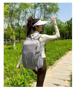 Detailed outdoor shot of the lightweight grey backpack showing strap and side pocket design.