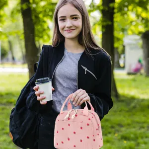 Girl carrying a pink corduroy strawberry lunch bag in an outdoor park setting