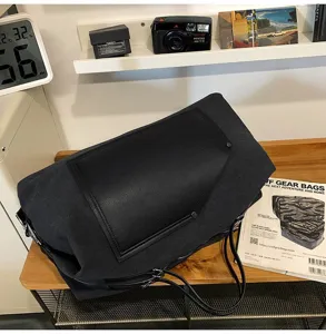 Vue détaillée d'un grand sac de voyage en toile avec rabat en cuir sur bureau en bois.