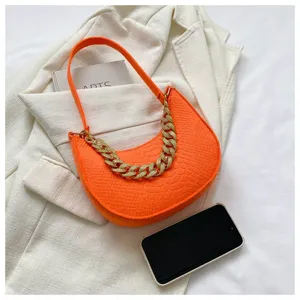 Detalle del bolso de hombro naranja en fieltro con patrón de cocodrilo y cadena dorada