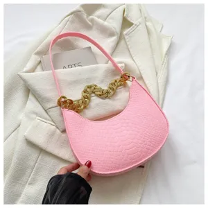 Detalle de bolso hobo de fieltro rosa con cadena dorada sobre fondo de blazer blanco