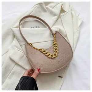 Detalle de bolso de axila de fieltro retro con cadena de oro gruesa sobre blazer blanco