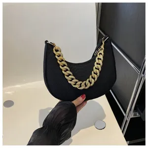 Primer plano de un bolso de media luna en fieltro negro con cadena dorada decorativa