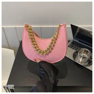 Detalle de un bolso hobo de fieltro rosa con cadena dorada gruesa y textura de serpiente
