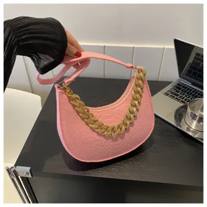 Primer plano de bolso de fieltro rosa con relieve de cocodrilo y cadena oro