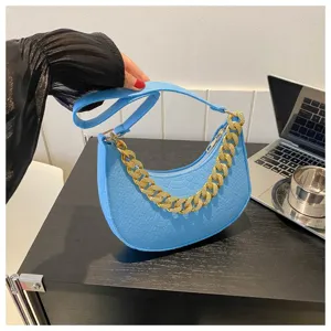 Elegante bolso de fieltro azul bajo el brazo con cadena dorada y correa