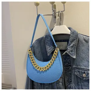 Vista detallada del bolso hobo de fieltro azul claro con cadena dorada sobre denim