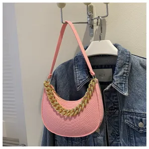 Detalle del bolso de media luna de fieltro rosa con cadena dorada y textura de coco